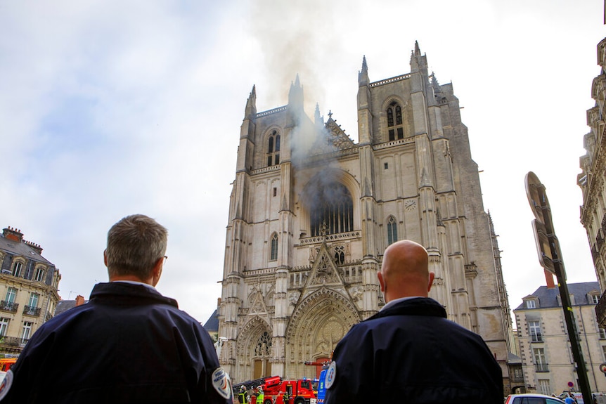 Two police officers look at  ablaze at the St Peter and St Paul Cathedral in Nantes, France.