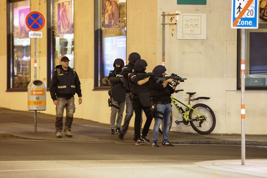 Police officers aim their weapons on the corner of a street in Vienna.