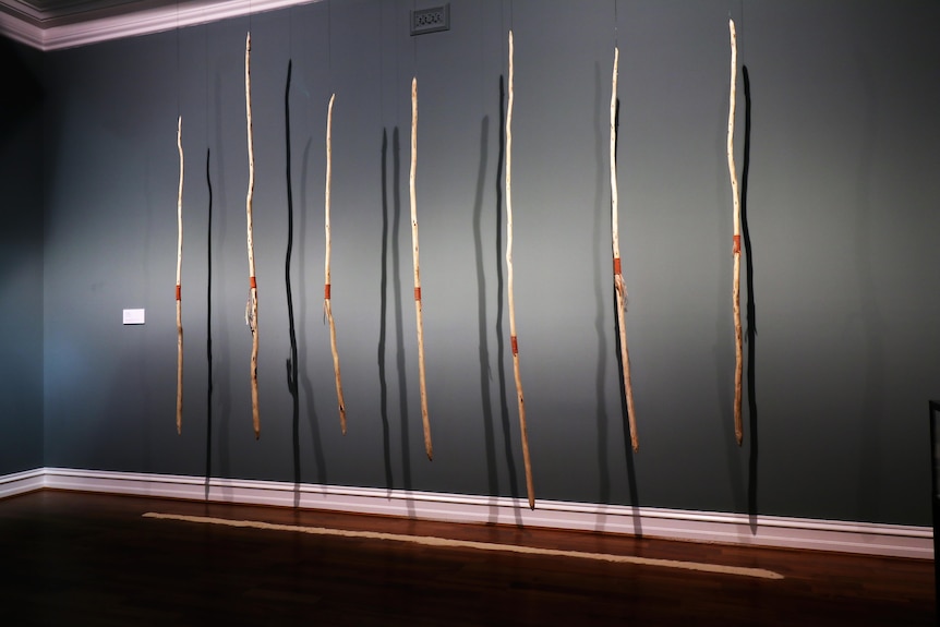 mounted and lit decorated, carved sticks in an art gallery