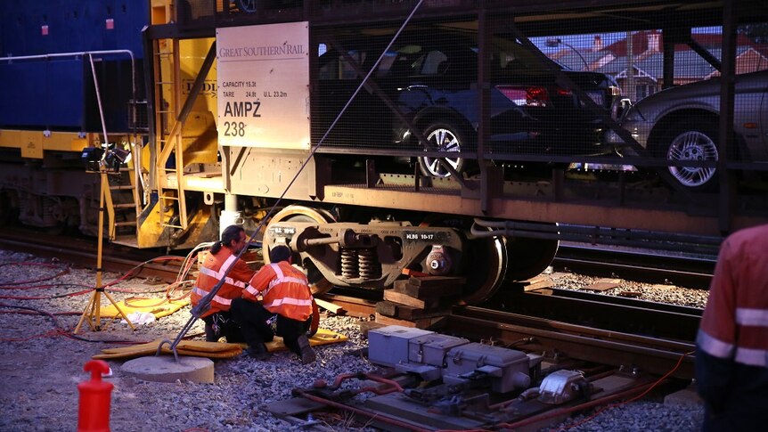 Workers examine the India Pacific train after a minor derailment in Perth.