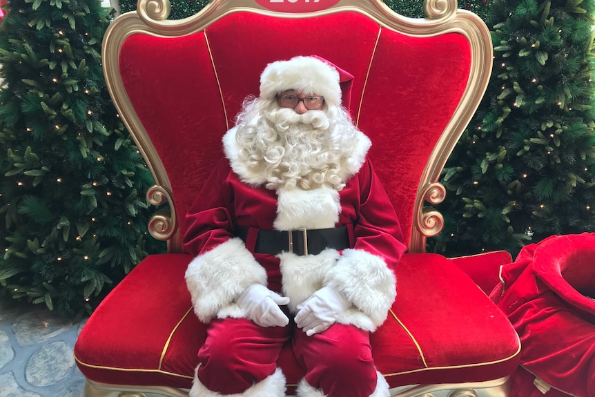 A shopping centre Santa sits alone on his grand red throne.