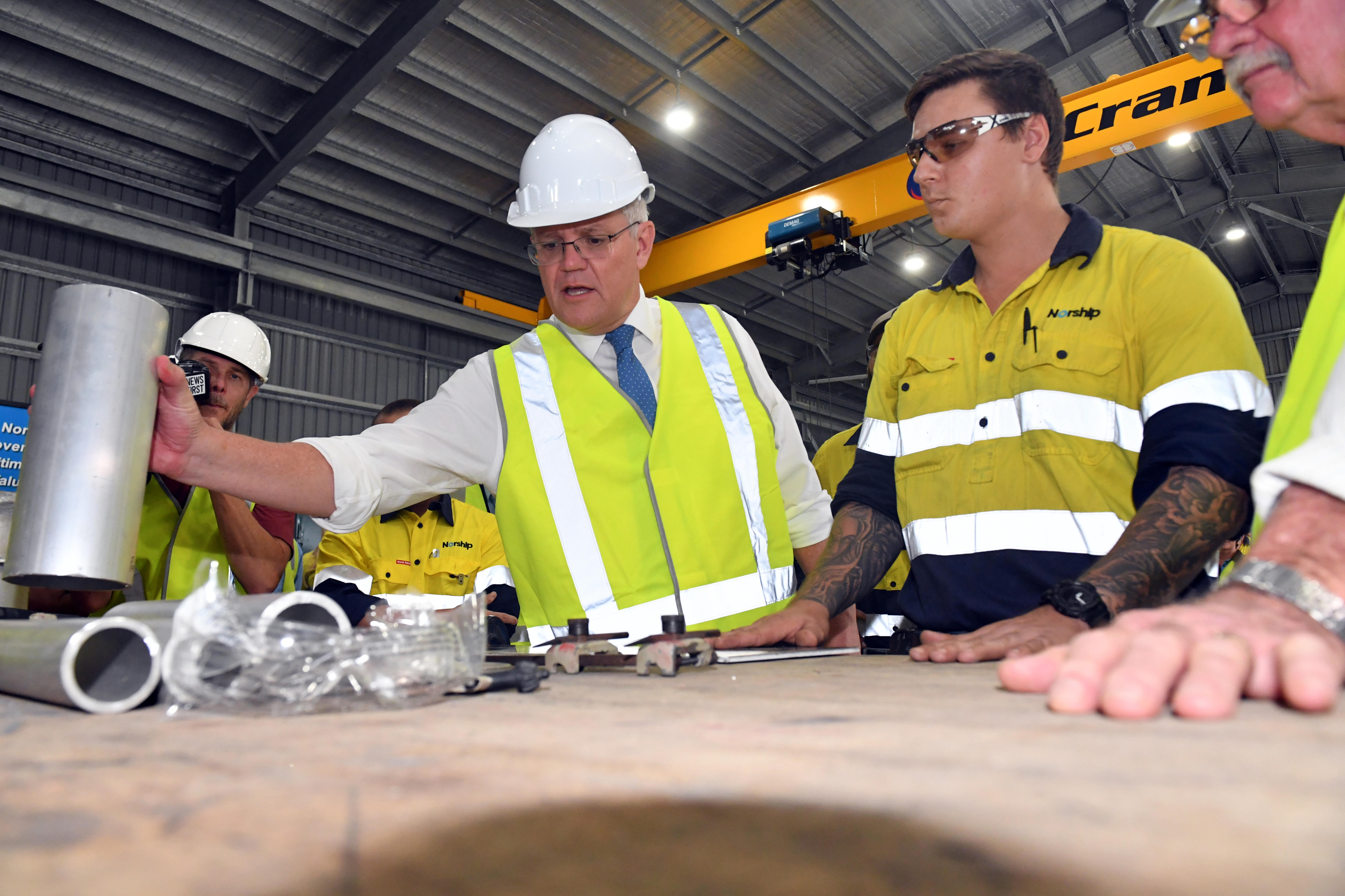 Scott Morrison touches metal pipes in a factory while wearing a hard hat and high-vis.