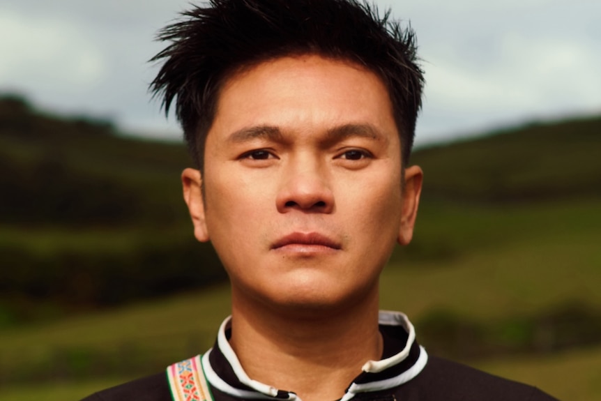 man looking at camera in black dress with weaving.