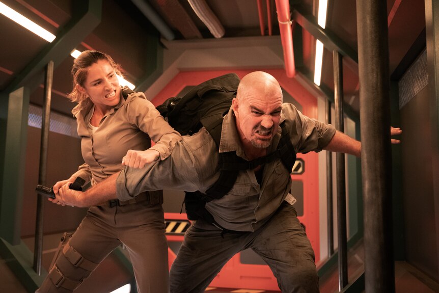 A movie still of an action scene showing a woman fighting a man