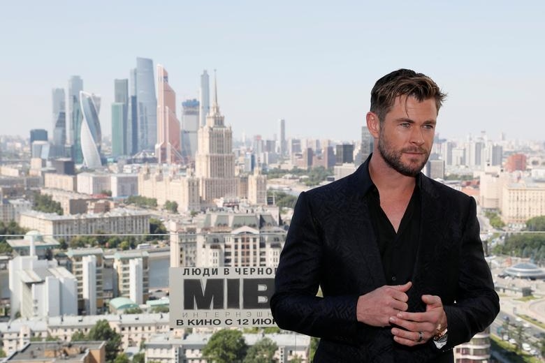 Chris Hemsworth, wearing a black suit, poses for a photo