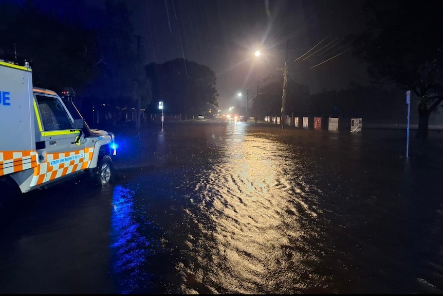 An SES vehicle parked on a flooded street at night.