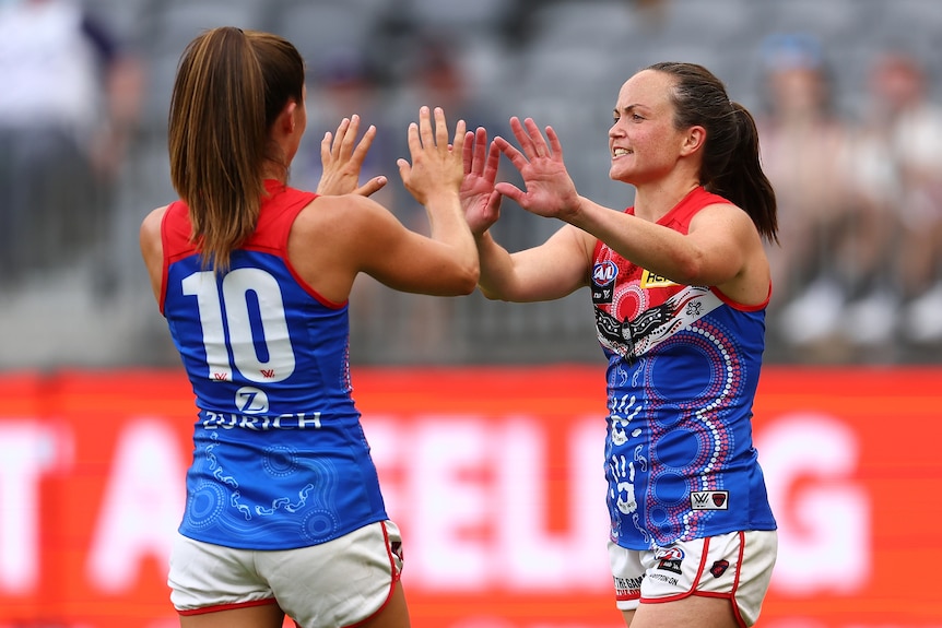 Kate Hore and Daisy Pearce high five after a goal against Fremantle. 
