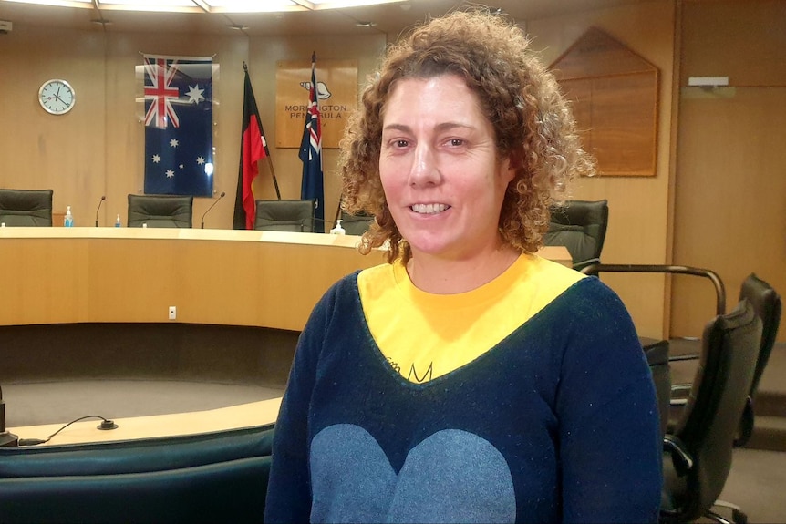 Sarah Race smiles as she stands inside a council chamber building.