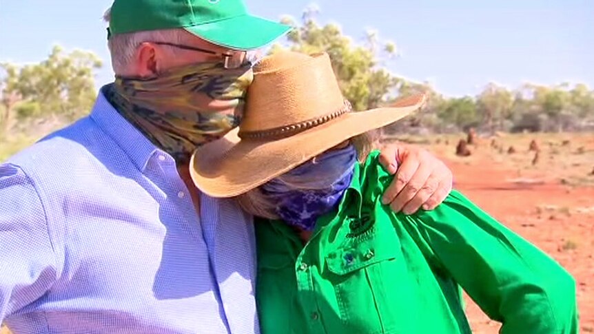 Scott Morrison, wearing a bandana, puts his arm around a grazier while standing on a property.