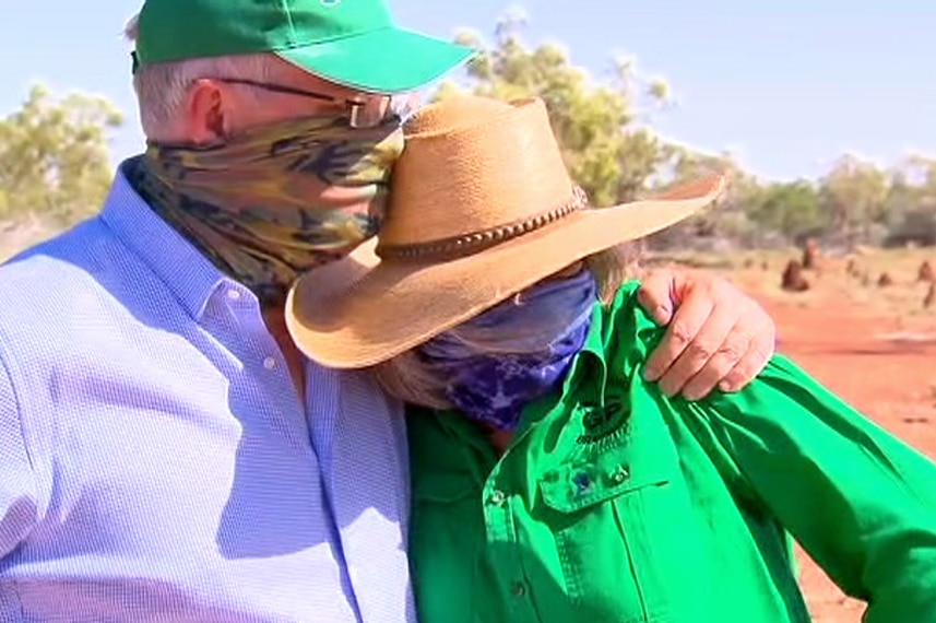 Scott Morrison, wearing a bandana, puts his arm around a grazier while standing on a property.