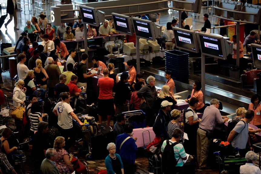 Stranded Qantas passengers line up as they seek information at the check-in counters