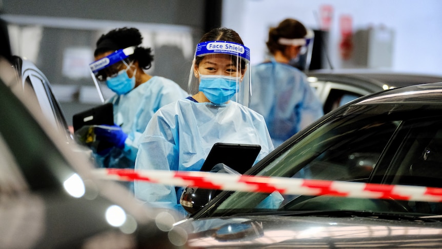 Health workers conduct tests for COVID-19 in a drive-through testing centre