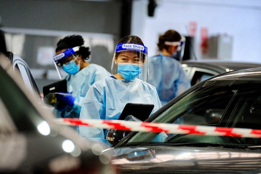 Health workers conduct tests for COVID-19 in a drive-through testing centre