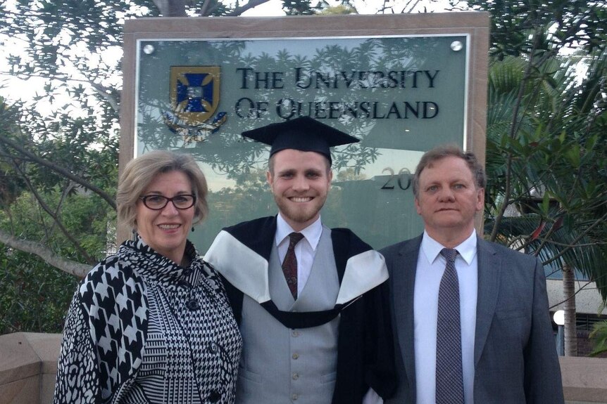 a woman, a young man and an older man standing in front of a university sign