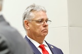Scot Peterson stands in a suit in a courtroom in Fort Lauderdale near two other people in suits
