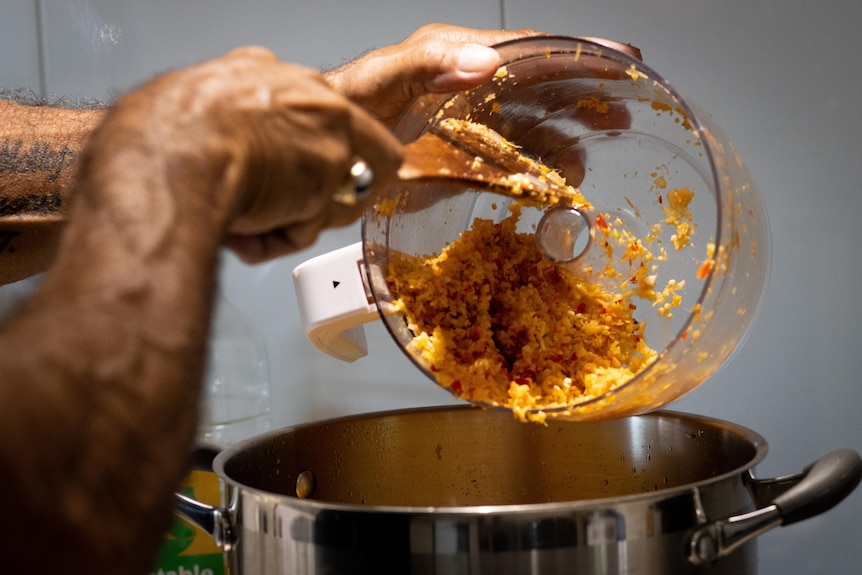 A finely cut mix of red chillies, ginger and garlic are added to a large pot.