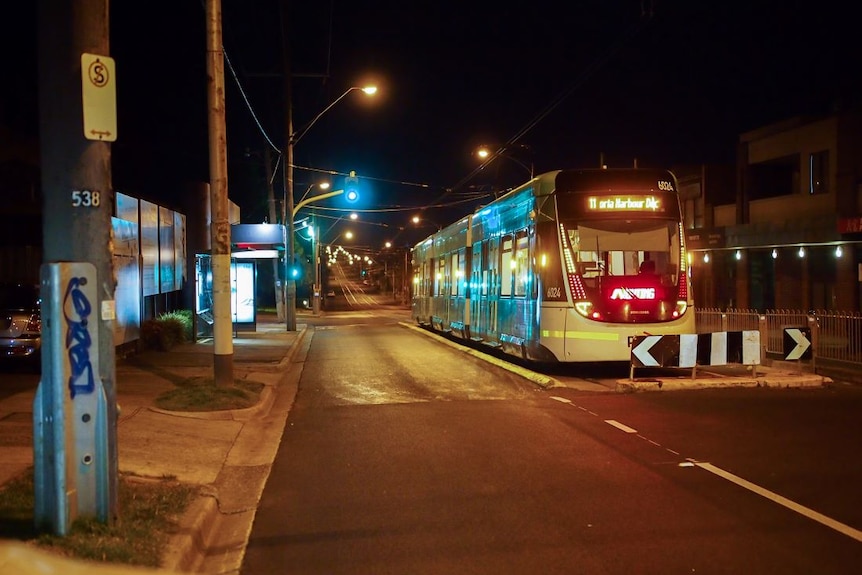 A tram waits on an empty street at night during Melbourne's coronavirus curfew.