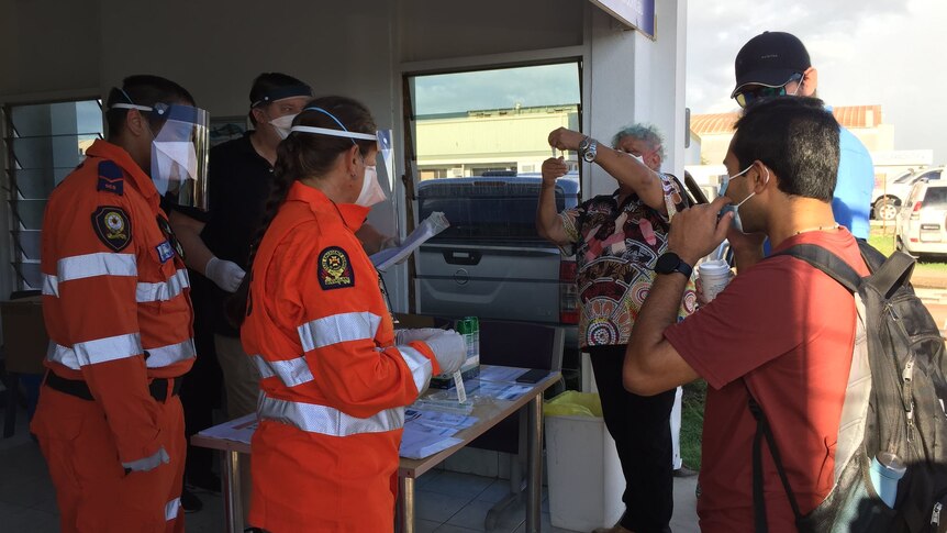 SES volunteers and health staff stand around a table at a ferry terminal.
