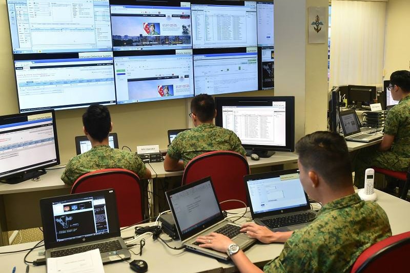 Singaporean military service personnel work on computers. 