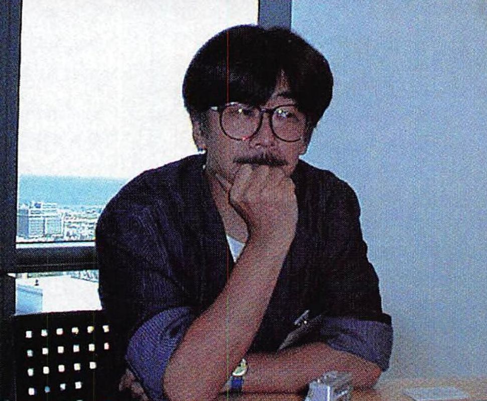 Japanese composer Nobuo Uematsu sits at a table, resting on elbow