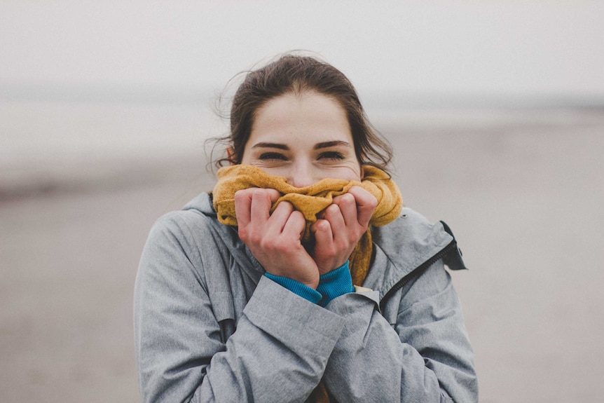 A girl wearing a warm jacket and big scarf around her face.