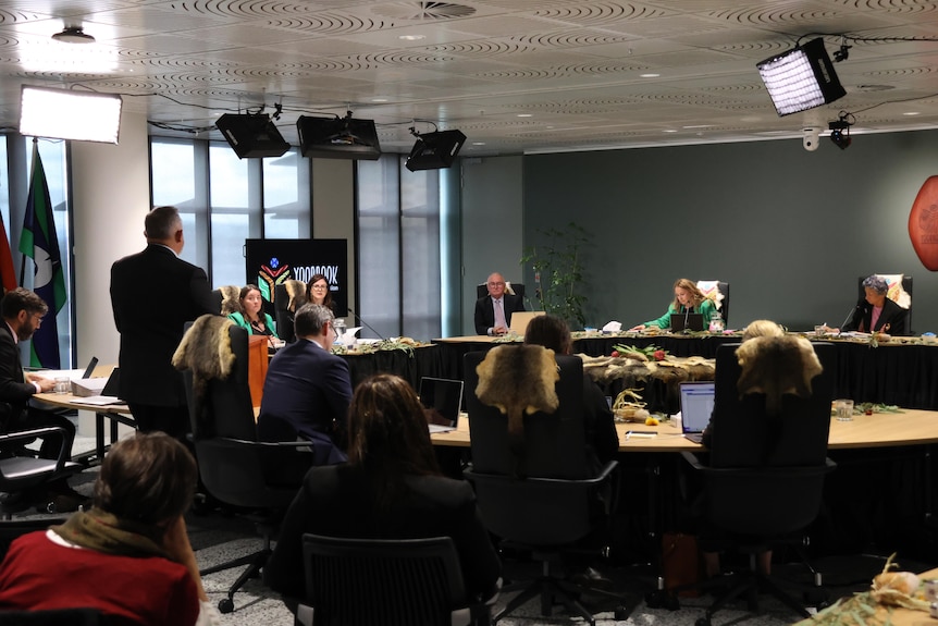 Two women in a meeting room being questioned by a man