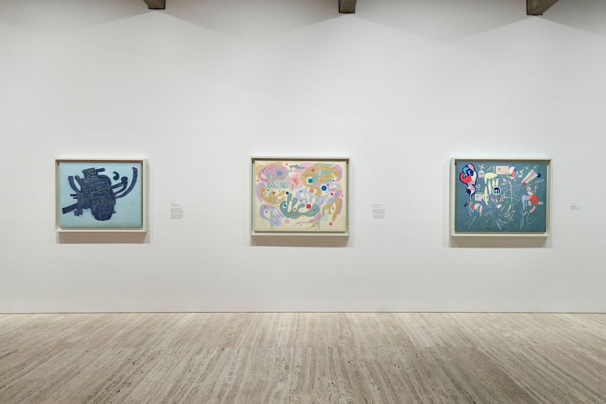 Installation view of colourful Kandinsky paintings hanging on white walls in a gallery.
