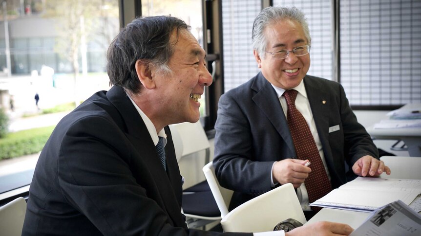 Two older Japanese men in suits laughing together