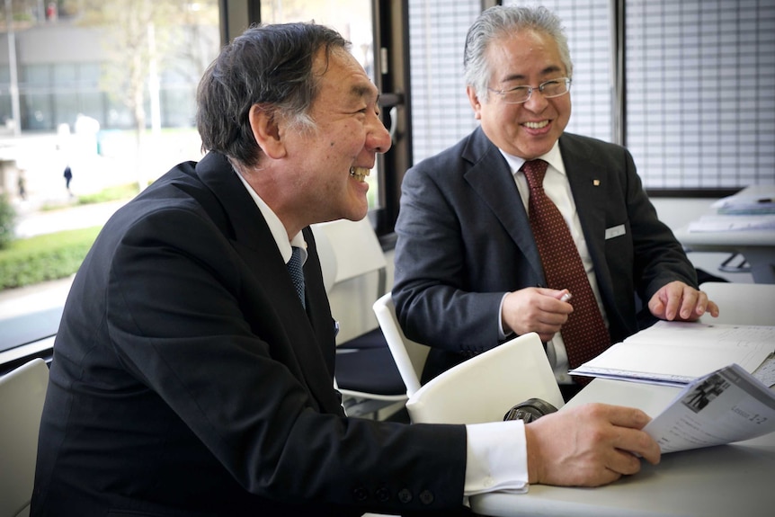 Two older Japanese men in suits laughing together