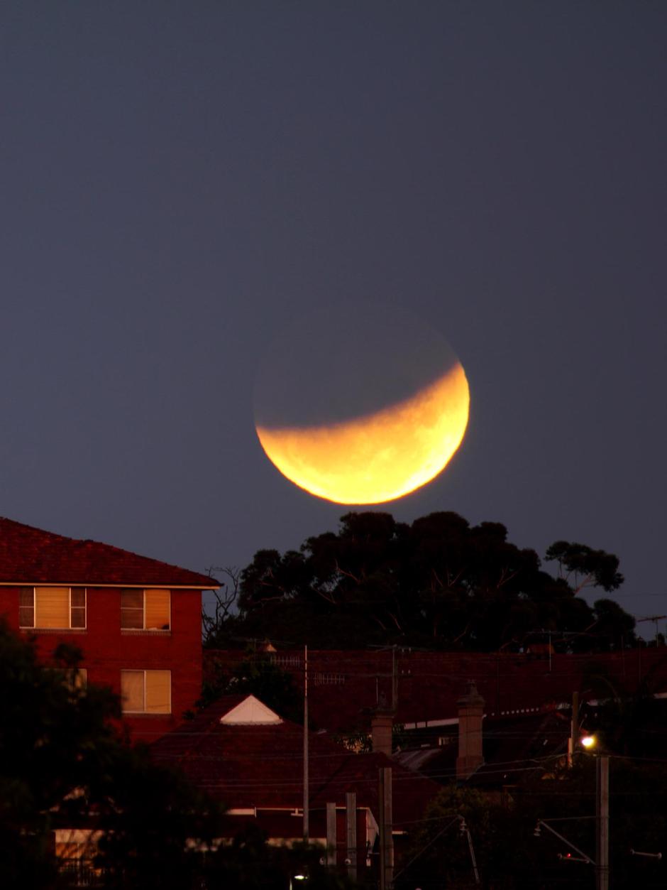 lunar eclipse over roofs of houses