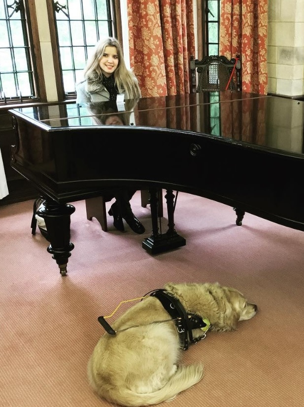 Singer Rachael Leahcar sits at a grand piano.