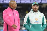 Aaron Finch walks off the MCG while speaking to the two umpires