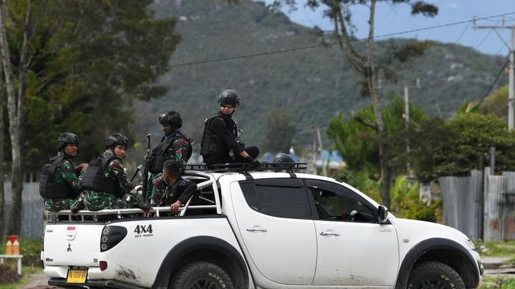 Indonesian soldiers and police officers sit on a car as they patrol in Wamena, Papua, Indonesia.