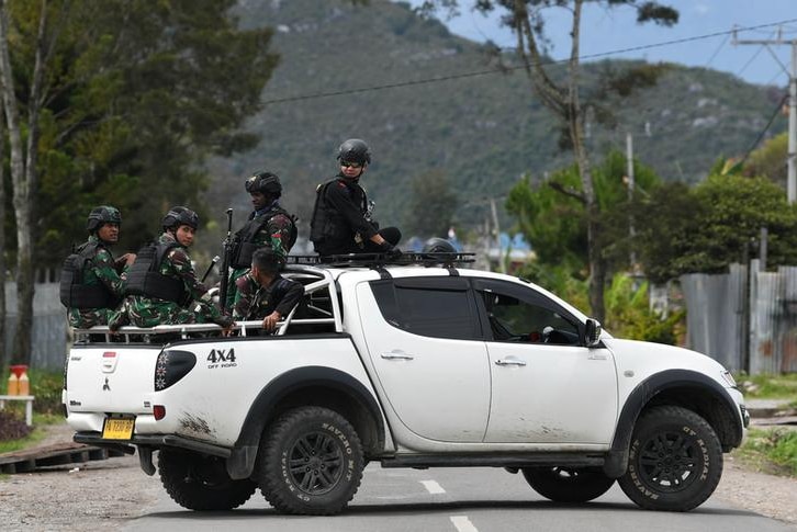 Indonesian soldiers and police officers sit on a car as they patrol in Wamena, Papua, Indonesia.