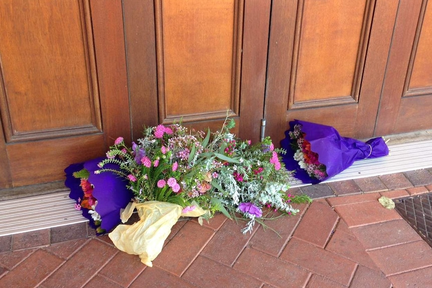bunch of flowers lying on ground outside doorway to Dome cafe