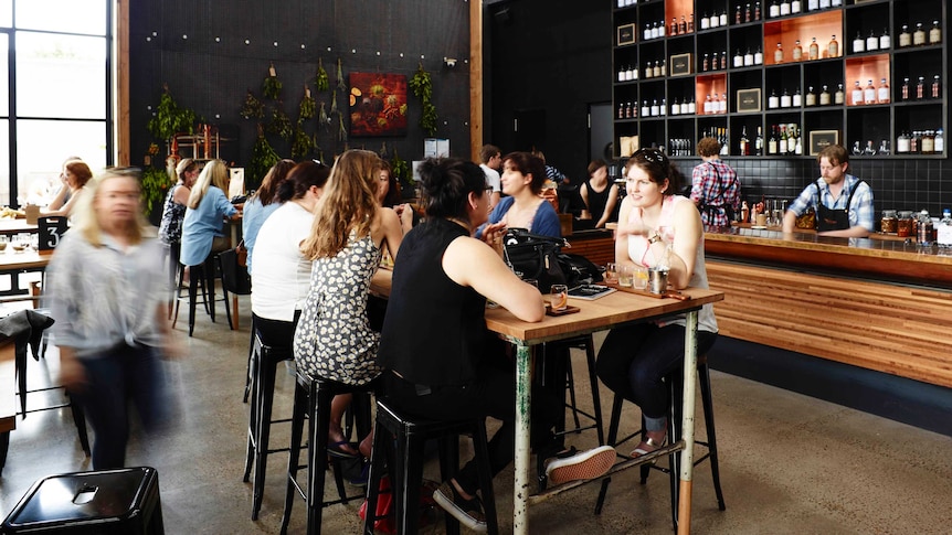 People sit at tables drinking in a large room lined with bottles of gin, Four Pillars in Yarra Valley Victoria