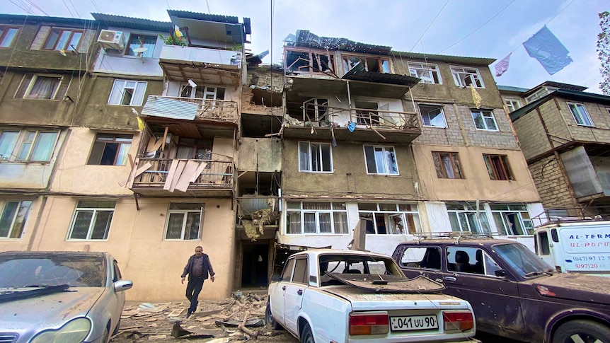 A damaged residential building and cars in the city of Stepanakert.