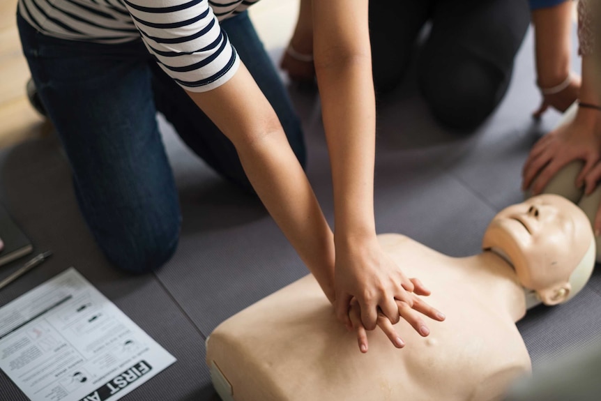 Female hands giving CPR to a dummy in a first aid class.