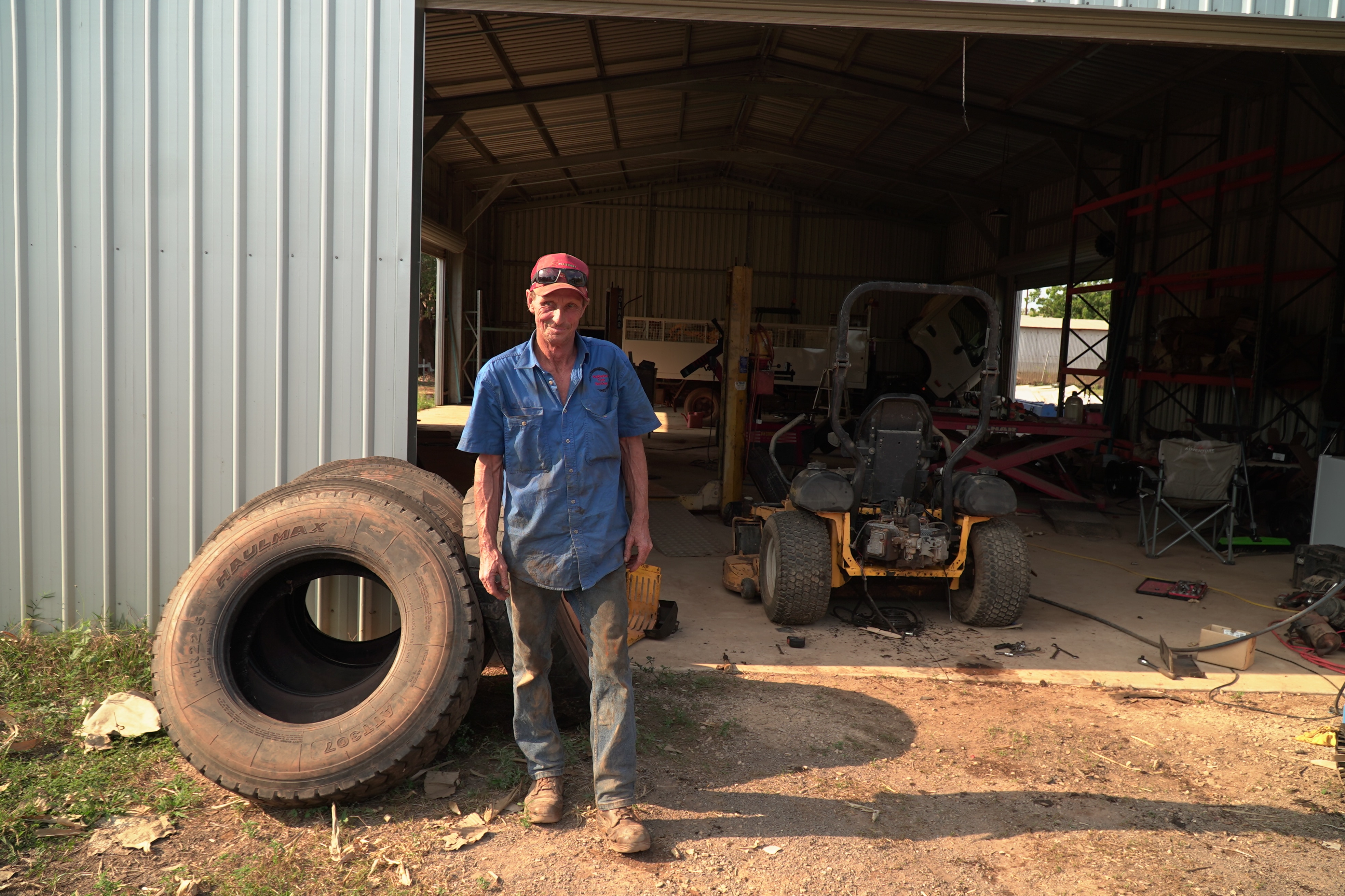 A man stands at the entrance of a large shed.