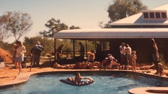People gather around and frolic in a pool the shape of Australia.