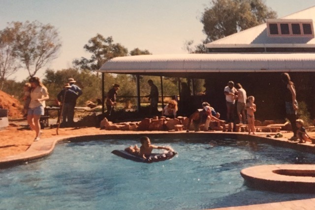 People gather around and frolic in a pool the shape of Australia.