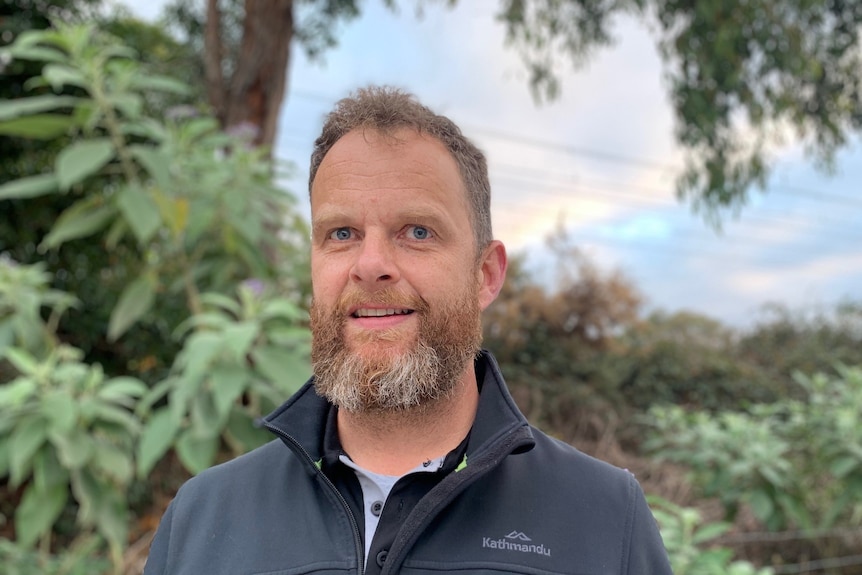 A man wearing a zipped-up navy jacket.