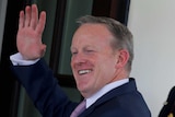 White House Press secretary Sean Spicer waves as he walks into the White House, soldier behind him