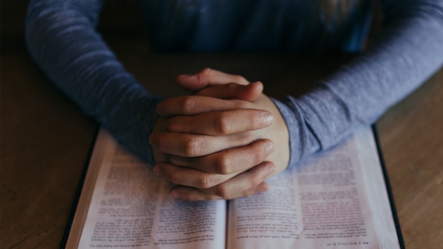 A woman prays over a bible.