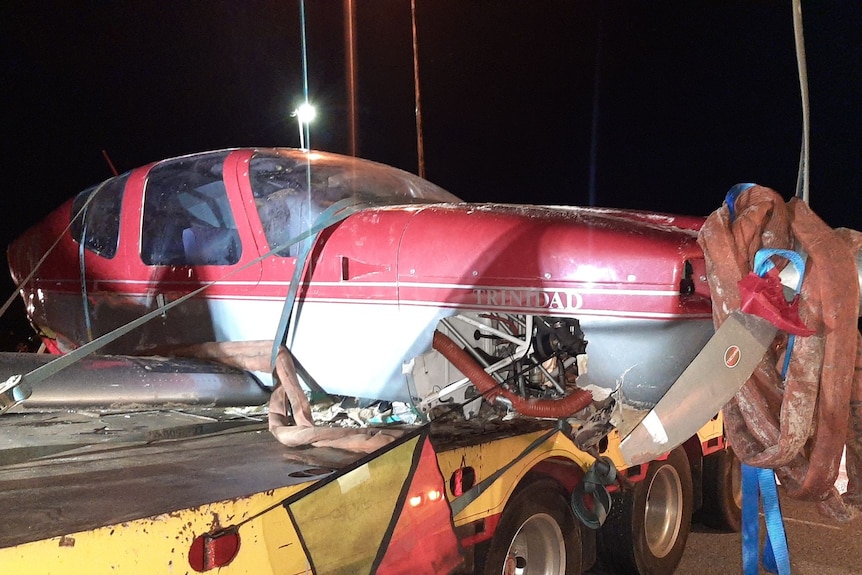 A photo of the wreckage of a red plane loaded on the back of a truck.