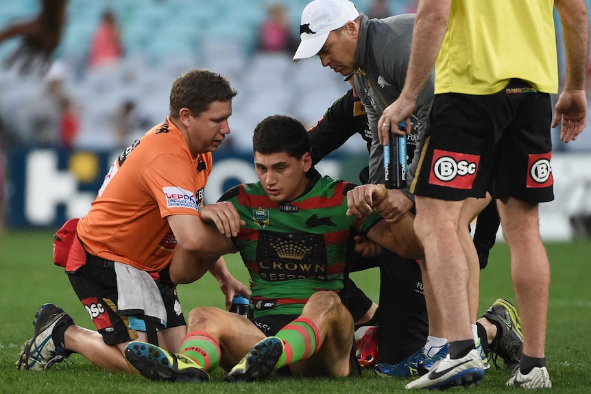 A rugby player is helped up by other players.