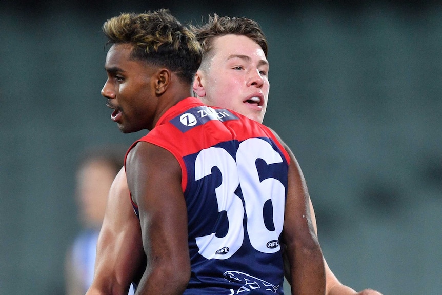 A Melbourne Demons AFL player embraces a teammate as he celebrates kicking a goal against the Kangaroos.