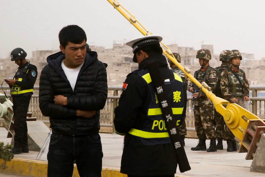 A police officer speaks to a man as security forces keep watch behind them.