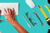 A woman's hands type on a keyboard surrounded by tools of various jobs and trades for a story about improve work and career.