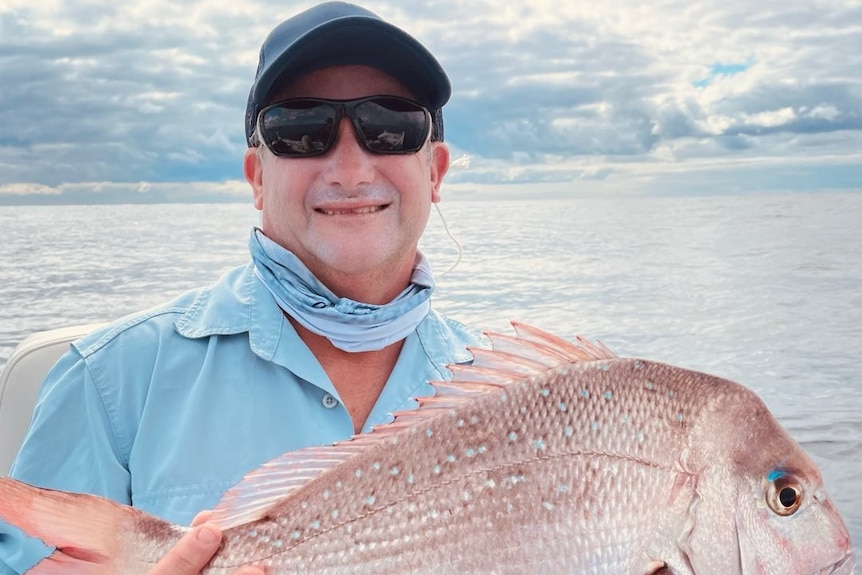 darren curmi holds a fish, he is the skipper and survivor of a boat accident that was hit by a whale in sydney